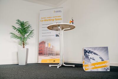 Eingangsbereich des Co-Working-Space mit Roll-up, Stehtisch für Flyer und Sitzwürfel