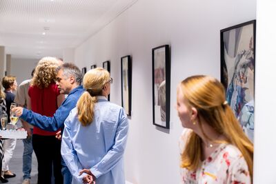 zeigt verschiedene Personen beim betrachten der Bilder aus der Ausstellung "Conni - Retrospektive" als Teil der Initiative Kunst im Co-Working-Space